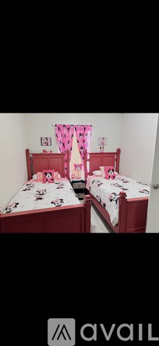 A bedroom with two beds and a pink curtain.