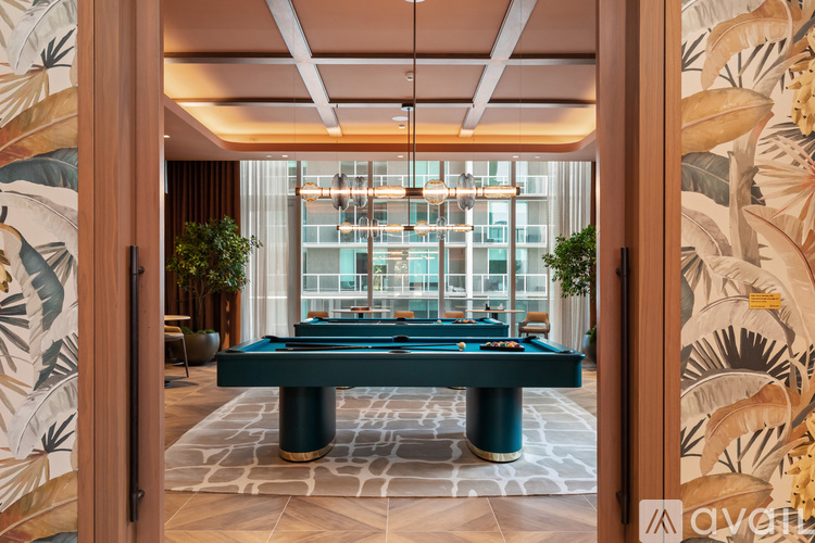 A pool table in a room with a view of a building outside the window.