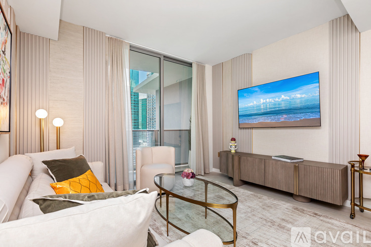 A modern living room with a white sofa and a large flat screen TV mounted on the wall.