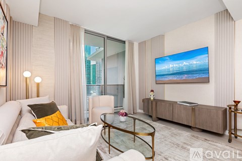 A modern living room with a white sofa and a large flat screen TV mounted on the wall.