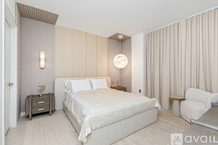 A bedroom with a large bed, a nightstand, and a chair.