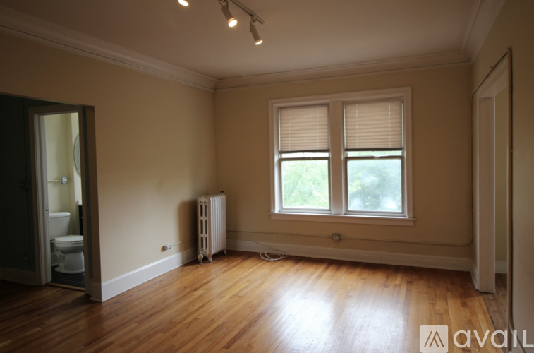 A room with wooden floors and a window with blinds.