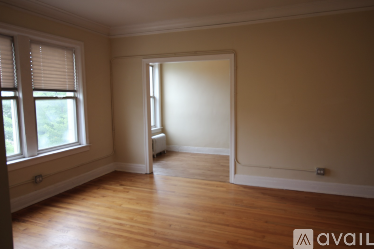 A room with wooden floors and a window with blinds.