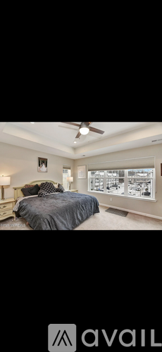 A bedroom with a large bed and a ceiling fan.