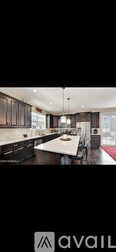 A modern kitchen with dark wood cabinets and a white island.
