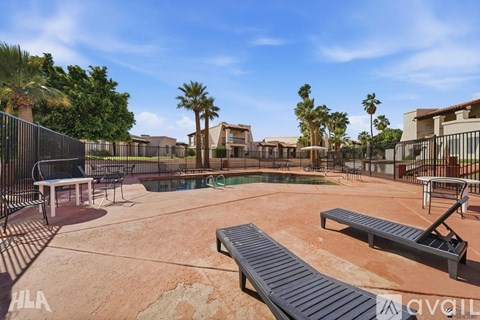 A pool surrounded by a black fence with a table and chairs in the middle.