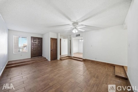 A spacious room with wooden flooring and a ceiling fan.