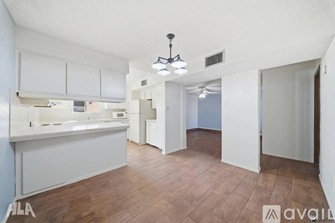 A spacious kitchen with white cabinets and a wooden floor.