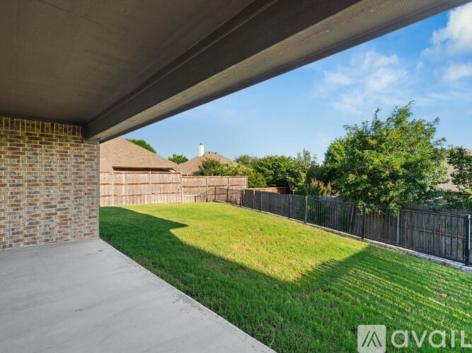 A concrete patio area with a brick wall and a grassy yard.