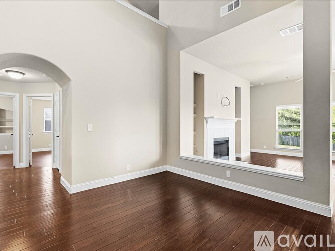 A spacious room with wood flooring and a large mirror on the wall.