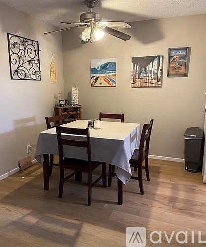 A dining room with a table set for two and a ceiling fan.