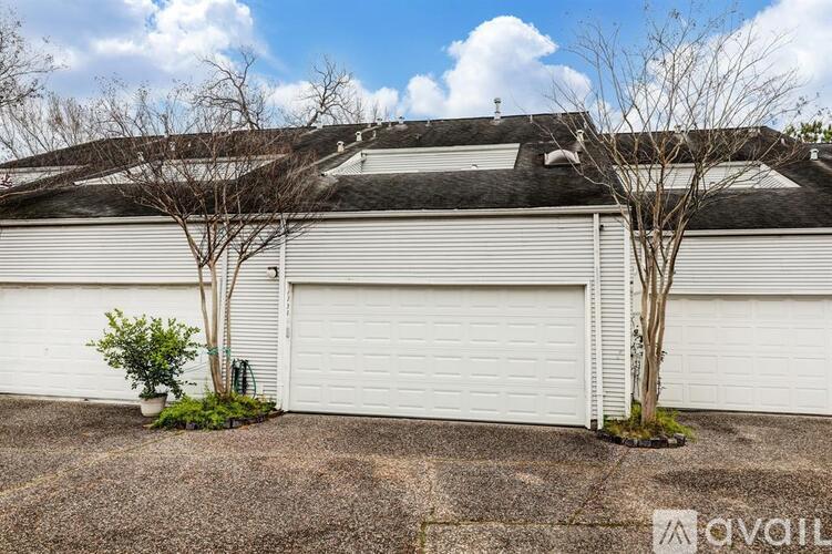 A white garage door is closed and there are two trees in front of it.