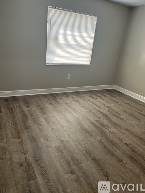 A room with wooden flooring and a window with blinds.