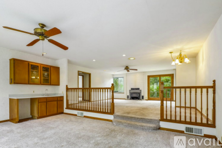 A spacious living room with a ceiling fan and a staircase leading to another room.