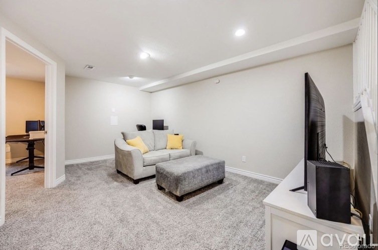 A living room with a grey couch and a grey ottoman.