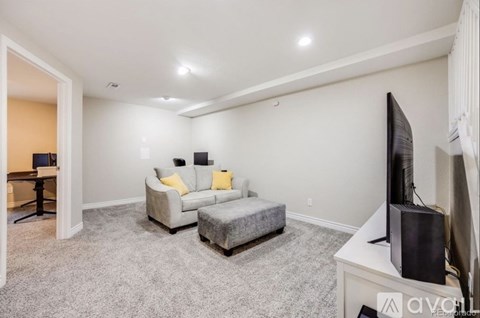 A living room with a grey couch and a grey ottoman.