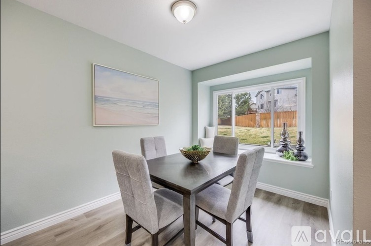 A dining room with a table and chairs and a painting on the wall.