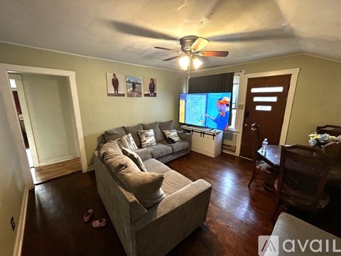 A living room with a grey couch and a television on the wall.