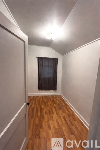 A room with wooden floors and a window with a black curtain.