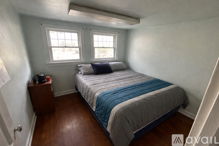 A bedroom with a bed, nightstand, and window.