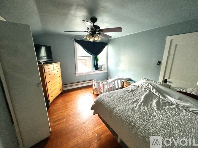 A bedroom with a bed, dresser, and window.