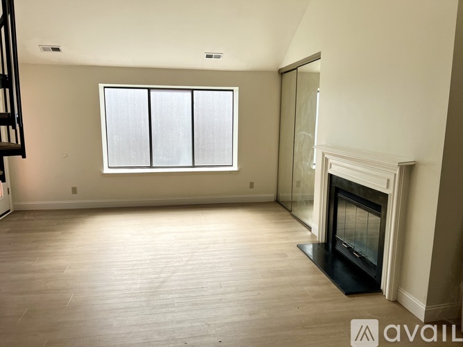 A spacious living room with a fireplace and a large window.