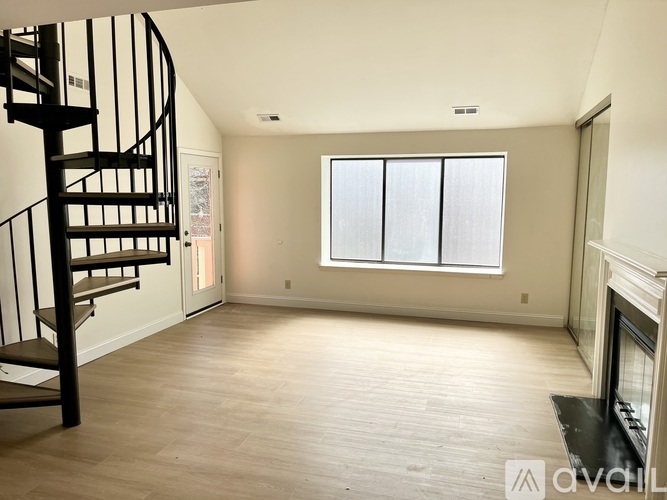 A living room with a spiral staircase and a fireplace.