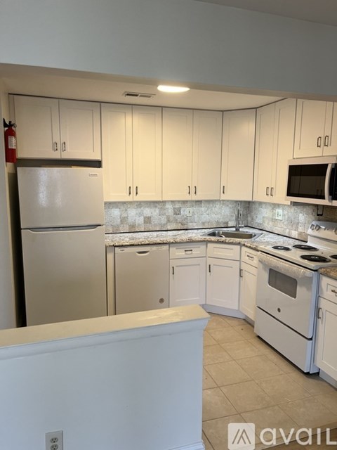 A kitchen with white cabinets and appliances.