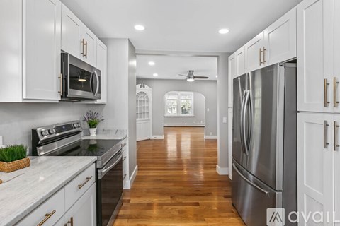 A kitchen with white cabinets and a stainless steel refrigerator.