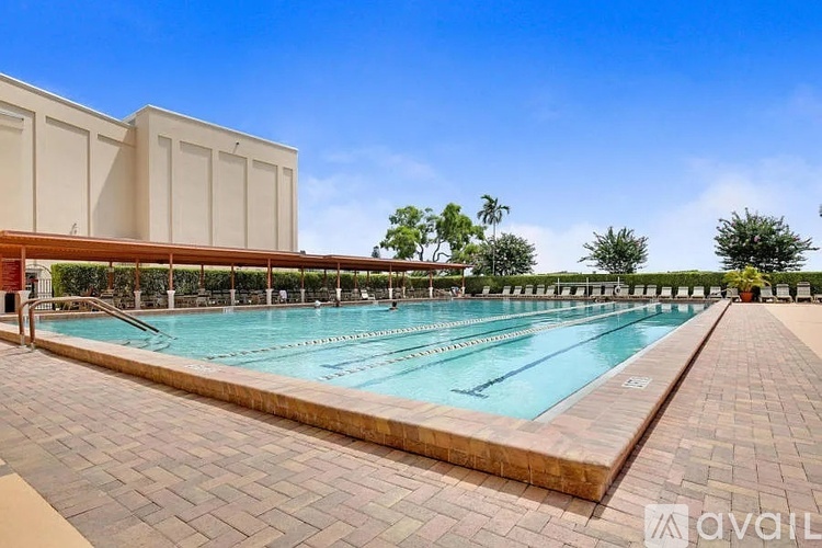 A large outdoor swimming pool with a red building in the background.