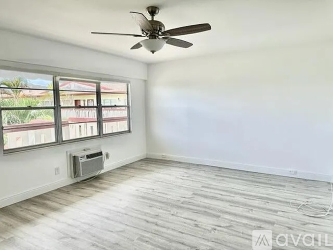 A room with a ceiling fan and a window overlooking a building.