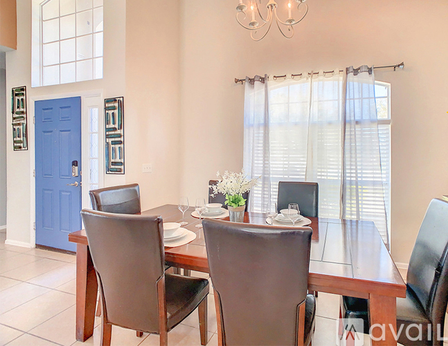 A dining room with a table set for two and a blue door.