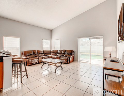A living room with a brown leather couch and a glass coffee table.