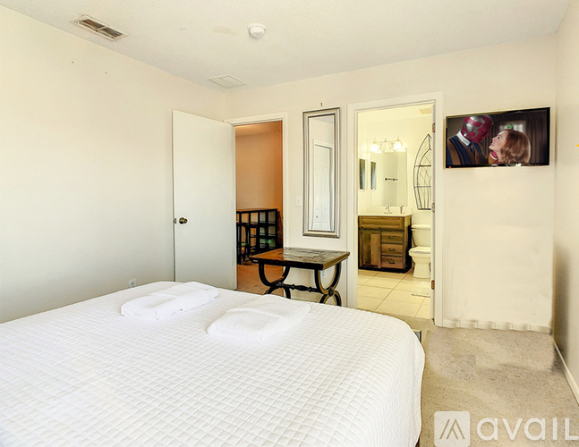 A bedroom with a large bed and a mirror on the wall.