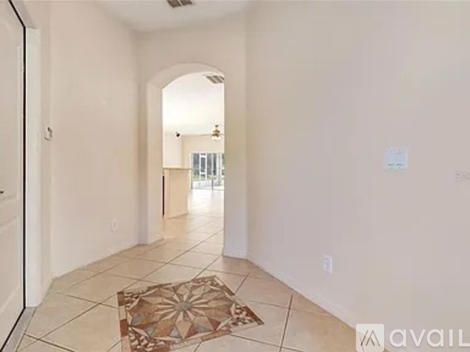 A hallway with a rug on the floor and a doorway leading to another room.