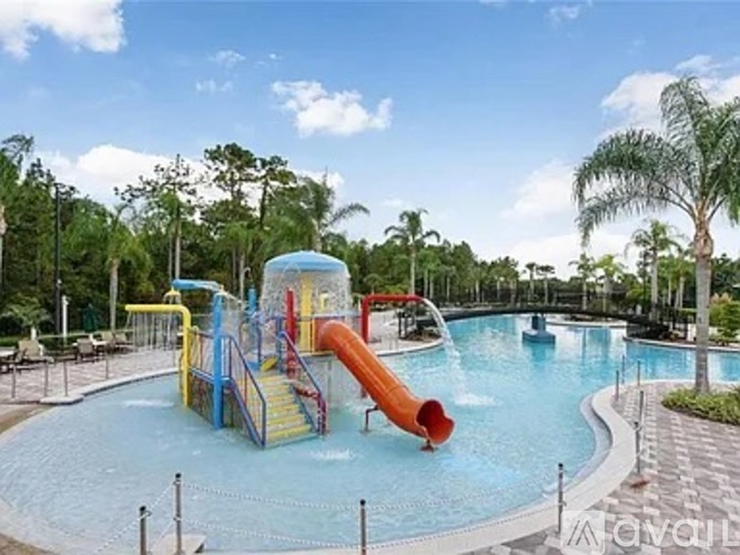 A water slide in a pool surrounded by trees.