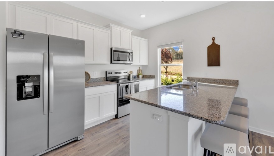 A modern kitchen with a stainless steel refrigerator and a granite countertop.