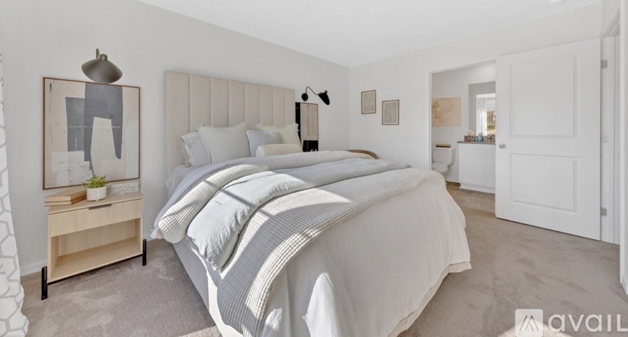 A bedroom with a large bed and a wooden nightstand.