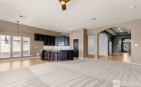 A spacious living room with a bar area and a ceiling fan.