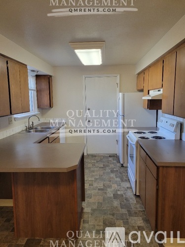 A kitchen with wooden cabinets and a tiled floor.