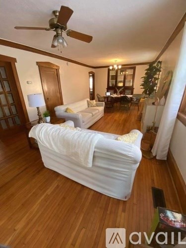A living room with a white sofa and wooden floors.