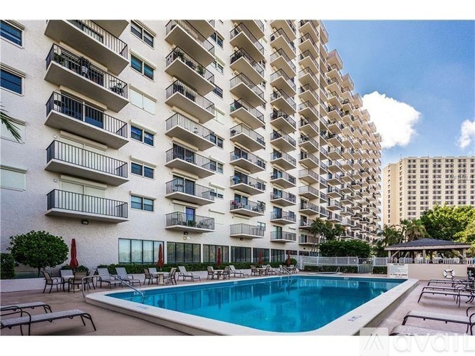 A tall apartment building with a pool in front.