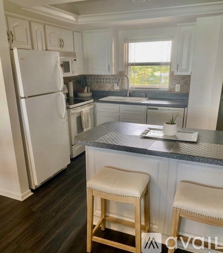A kitchen with white appliances and wooden stools.