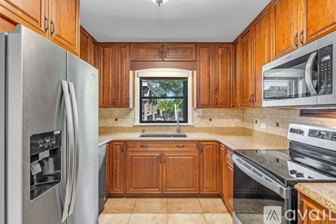 A kitchen with wooden cabinets and a stainless steel refrigerator.