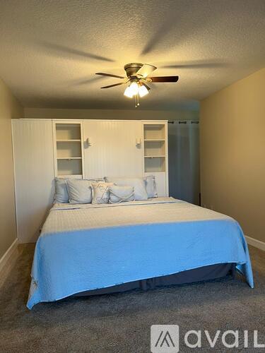 A bedroom with a bed, a ceiling fan, and a cabinet.