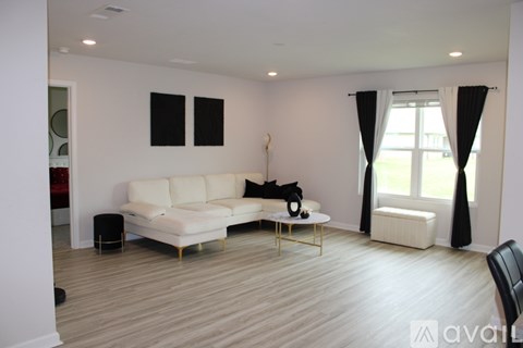 A living room with a white couch and a black dog.