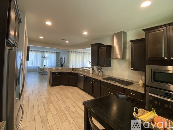 A kitchen with dark brown cabinets and a black countertop.