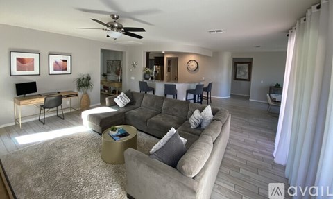 A living room with a grey couch and a ceiling fan.