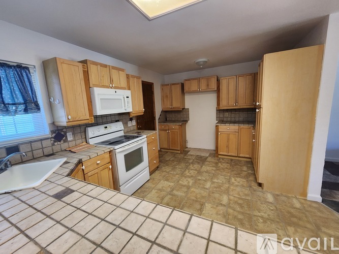 A kitchen with wooden cabinets and a tiled floor.