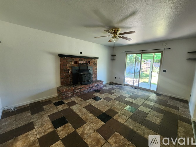 A living room with a fireplace and a ceiling fan.